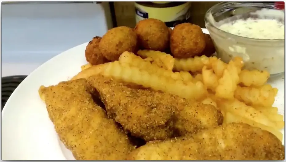 Fried red snapper, french fries, hush puppies, and potato salad on a plate